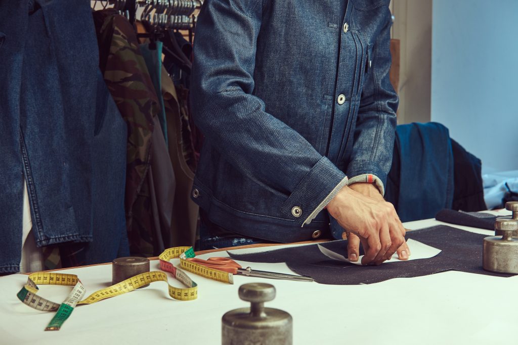 Cropped image of a tailor working with cloth samples at a sewing workshop.